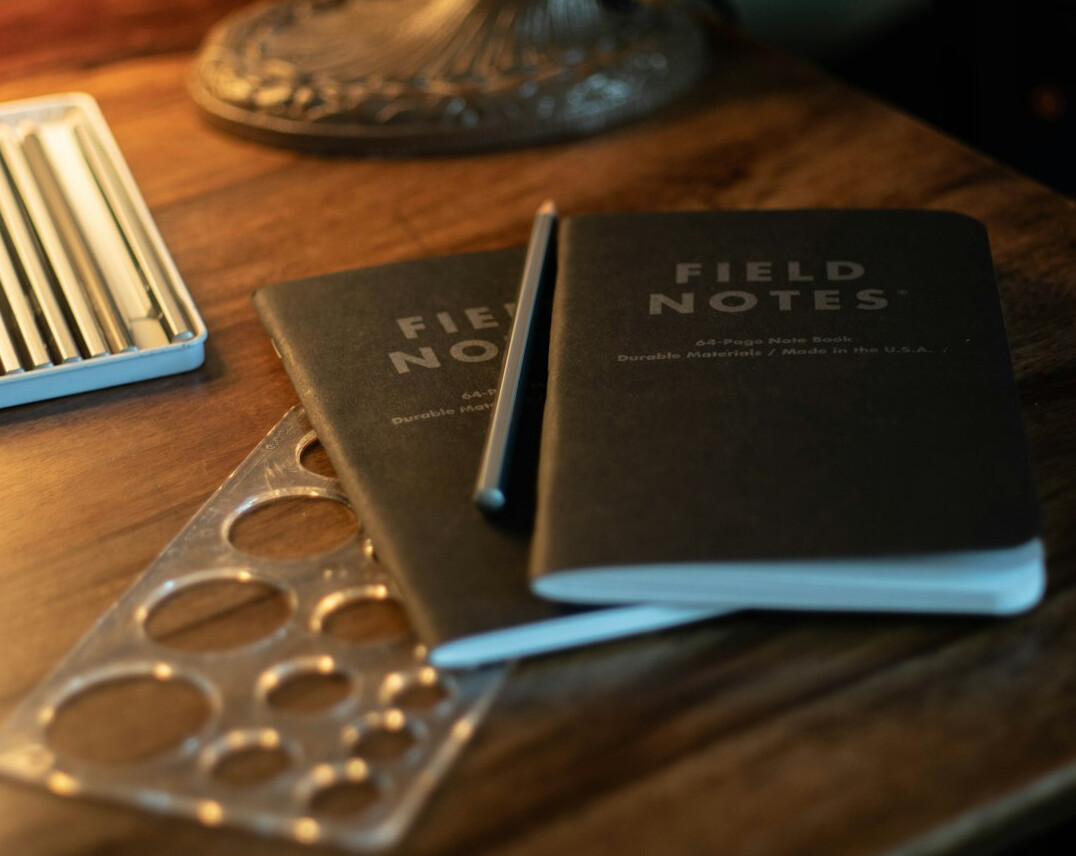 Vintage notebook with magnifying glass and pen on a wooden desk